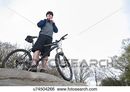 Mature male mountain biker fastening helmet on rock formation View Large Photo Image Stock Photograph - Mature male mountain biker fastening helmet on rock formation. Fotosearch