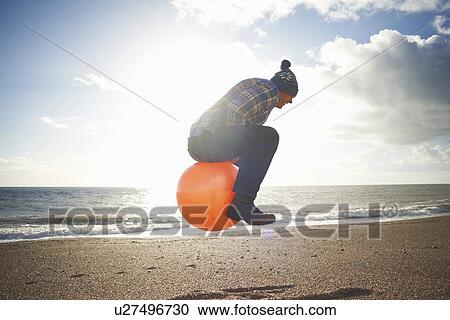 Mature man jumping mid air on inflatable hopper at beach View Large Photo Image Stock Image - Mature man jumping mid air on inflatable hopper at beach. Fotosearch