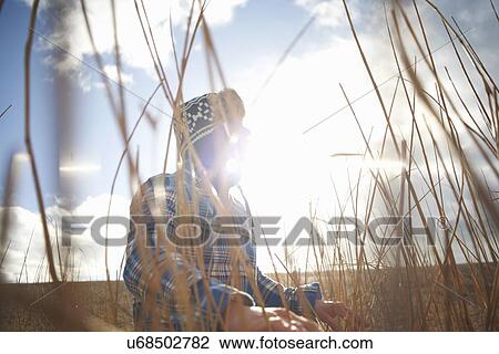 Stock Image - Mature man looking out from sunlit reeds. Fotosearch