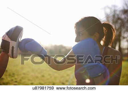 Stock Photo - Mature woman boxer training in field. Fotosearch