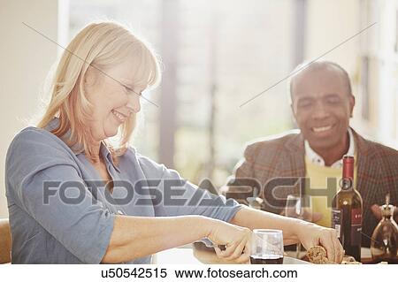 Stock Photography - "Mature woman cutting bread, senior man smiling". Fotosearch