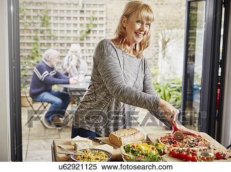 Stock Photography - Mature woman cutting pizza. Fotosearch
