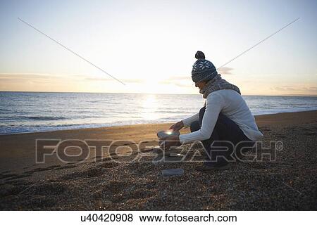 Mature woman stacking stones on beach at dusk View Large Photo Image Stock Photo - Mature woman stacking stones on beach at dusk. Fotosearch