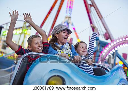 Stock Photo - Mature woman with son and daughter on fairground ride. Fotosearch