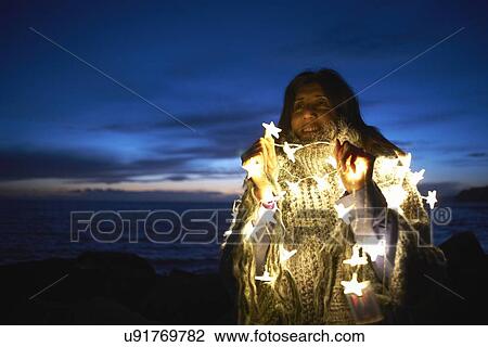 Mature woman wrapped in shawl with star fairy lights on beach at night View Large Photo Image Stock Image - Mature woman wrapped in shawl with star fairy lights on beach at night. Fotosearch