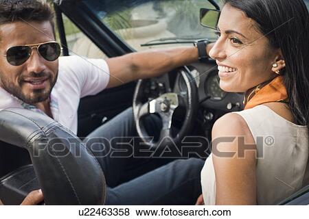 Stock Photo - "Mid adult couple in convertible car, rear view". Fotosearch