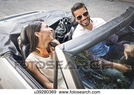 Stock Photo - "Mid adult couple in convertible car, elevated view". Fotosearch