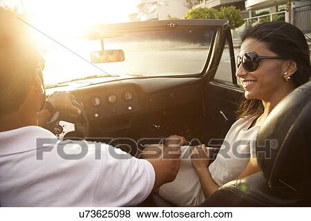 Stock Photo - "Mid adult couple in convertible car, rear view, close-up". Fotosearch