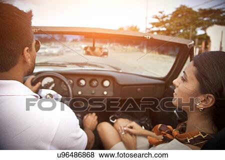 Stock Photo - "Mid adult couple in convertible car, rear view". Fotosearch