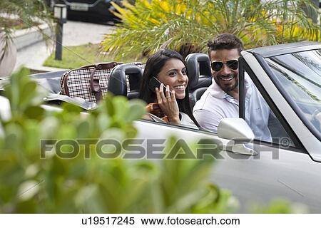 "Mid adult couple in convertible car, woman using smartphone" View Large Photo Image Stock Photography - "Mid adult couple in convertible car, woman using smartphone". Fotosearch