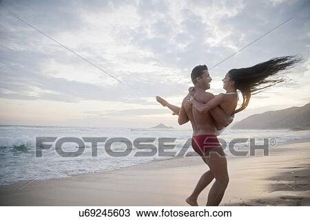 "Mid adult couple on beach, man carrying woman in arms, rear view" View Large Photo Image Stock Image - "Mid adult couple on beach, man carrying woman in arms, rear view". Fotosearch