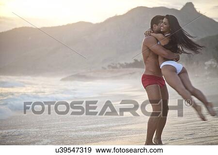 "Mid adult couple on beach, wearing swimwear, man swinging woman round" View Large Photo Image Stock Photo - "Mid adult couple on beach, wearing swimwear, man swinging woman round". Fotosearch