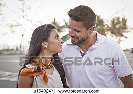 Stock Image - "Mid adult couple, outdoors, face to face, smiling". Fotosearch