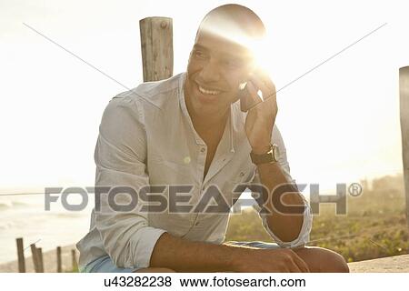 "Mid adult man chatting on smartphone at beach, Rio De Janeiro, Brazil" View Large Photo Image Stock Photo - "Mid adult man chatting on smartphone at beach, Rio De Janeiro, Brazil". Fotosearch