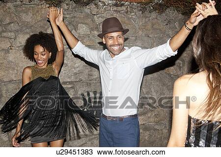 Mid adult man dancing with two young women View Large Photo Image Stock Image - Mid adult man dancing with two young women. Fotosearch