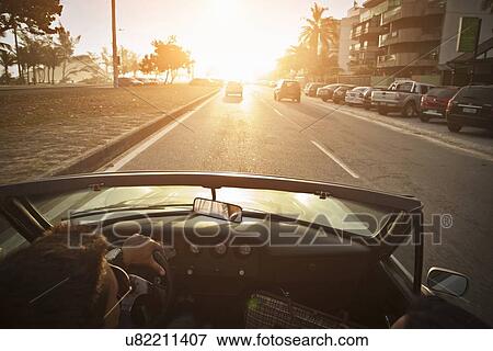 Stock Photo - "Mid adult man driving convertible car, elevated view". Fotosearch
