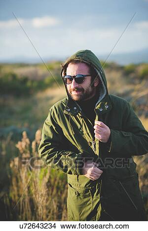 Picture - "Mid adult man fastening anorak at coast, Sorso, Sassari, Sardinia, Italy". Fotosearch