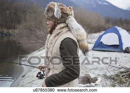 Stock Image - Mid adult man fishing. Fotosearch