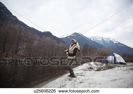 Stock Photograph - Mid adult man fishing. Fotosearch