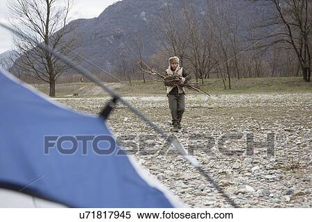 Stock Photography - Mid adult man gathering firewood. Fotosearch