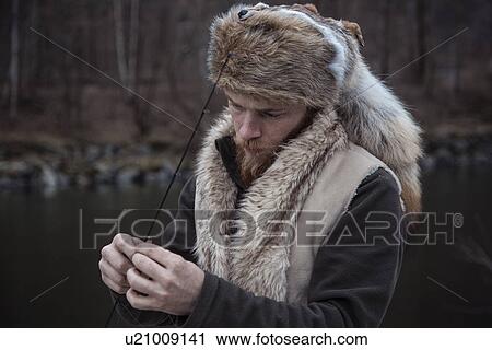 Stock Image - Mid adult man holding fishing line. Fotosearch