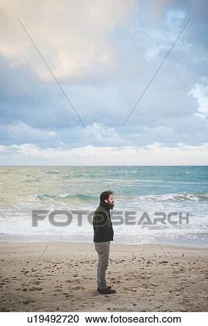 Stock Image - "Mid adult man on stormy beach, Sorso, Sassari, Sardinia, Italy". Fotosearch