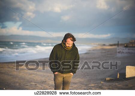 Stock Photo - "Mid adult man on stormy beach, Sorso, Sassari, Sardinia, Italy". Fotosearch