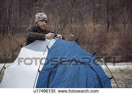 Stock Photography - Mid adult man putting up tent. Fotosearch
