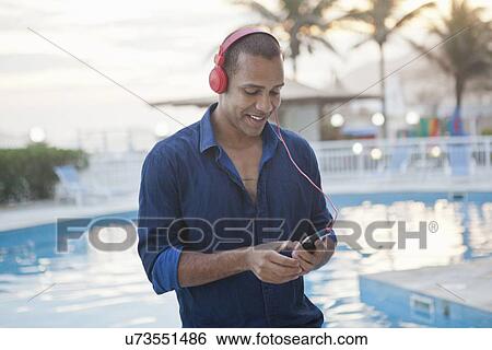 "Mid adult man selecting smartphone music at hotel poolside, Rio De Janeiro, Brazil" View Large Photo Image Stock Photograph - "Mid adult man selecting smartphone music at hotel poolside, Rio De Janeiro, Brazil". Fotosearch