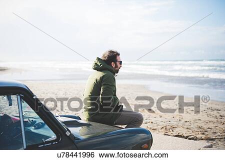 "Mid adult man sitting on vintage car on beach, Sorso, Sassari, Sardinia, Italy" View Large Photo Image Stock Photograph - "Mid adult man sitting on vintage car on beach, Sorso, Sassari, Sardinia, Italy". Fotosearch
