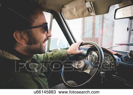 Mid adult man smiling whilst driving vintage car View Large Photo Image Stock Image - Mid adult man smiling whilst driving vintage car. Fotosearch