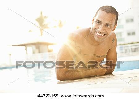 Stock Photo - "Mid adult man standing in sunlit hotel swimming pool, Rio De Janeiro, Brazil". Fotosearch