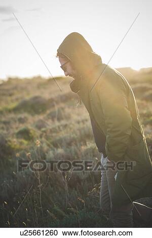 Mid adult man strolling in sunlit field View Large Photo Image Stock Image - Mid adult man strolling in sunlit field. Fotosearch