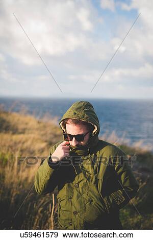 Stock Photo - "Mid adult man strolling on windy coast, Sorso, Sassari, Sardinia, Italy". Fotosearch