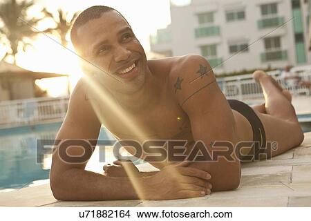 "Mid adult man sunbathing at sunlit hotel swimming pool, Rio De Janeiro, Brazil" View Large Photo Image Picture - "Mid adult man sunbathing at sunlit hotel swimming pool, Rio De Janeiro, Brazil". Fotosearch