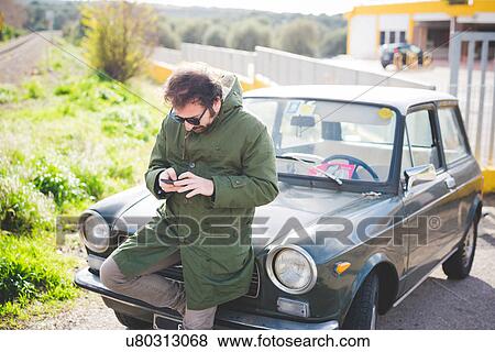 Mid adult man texting on smartphone next to railway track View Large Photo Image Stock Photo - Mid adult man texting on smartphone next to railway track. Fotosearch