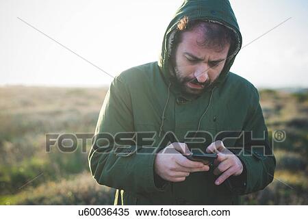 Mid adult man using smartphone whilst chewing matchstick in field View Large Photo Image Stock Photography - Mid adult man using smartphone whilst chewing matchstick in field. Fotosearch