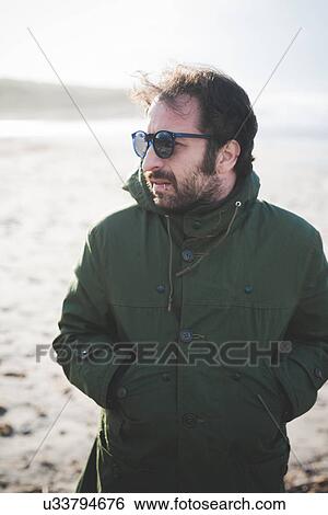 "Mid adult man wearing sunglasses on windy beach, Sorso, Sassari, Sardinia, Italy" View Large Photo Image Stock Photograph - "Mid adult man wearing sunglasses on windy beach, Sorso, Sassari, Sardinia, Italy". Fotosearch