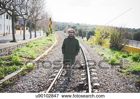Mid adult man wearing sunglasses strolling on railway track View Large Photo Image Stock Photo - Mid adult man wearing sunglasses strolling on railway track. Fotosearch