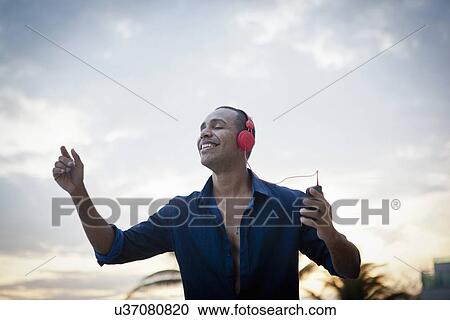 "Mid adult man with eyes closed listening to headphone music at beach, Rio De Janeiro, Brazil" View Large Photo Image Stock Image - "Mid adult man with eyes closed listening to headphone music at beach, Rio De Janeiro, Brazil". Fotosearch