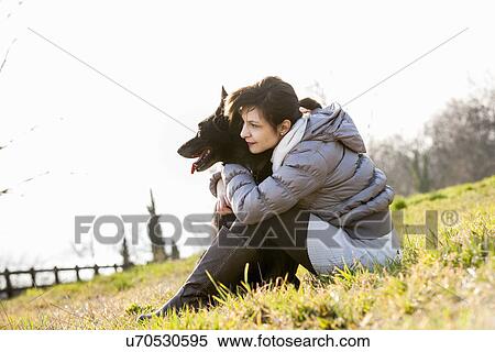 Mid adult woman and her dog sitting on hillside View Large Photo Image Stock Photography - Mid adult woman and her dog sitting on hillside. Fotosearch