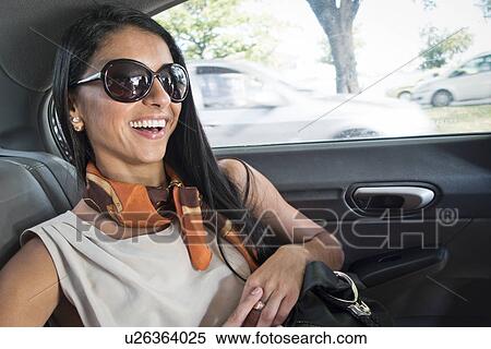 Stock Photography - "Mid adult woman in back of car, smiling". Fotosearch