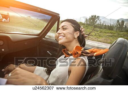 Stock Photo - Mid adult woman in passenger seat of convertible car. Fotosearch