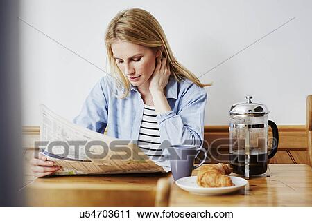 Stock Image - Mid adult woman reading newspaper. Fotosearch