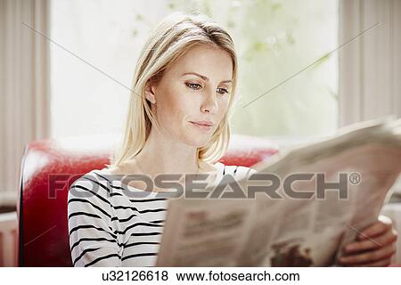 Stock Photo - Mid adult woman reading newspaper. Fotosearch