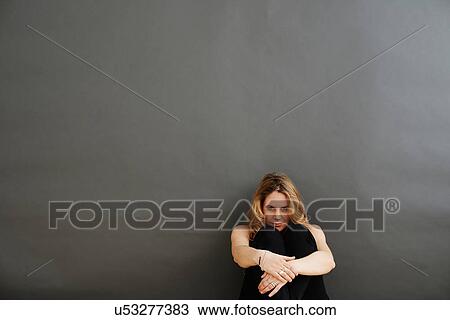 Mid adult woman sitting hugging knees to chest View Large Photo Image Stock Image - Mid adult woman sitting hugging knees to chest. Fotosearch