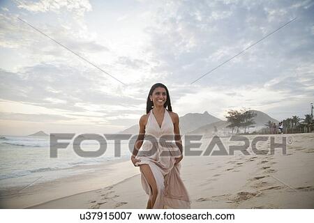 Stock Photo - Mid adult woman walking along beach. Fotosearch