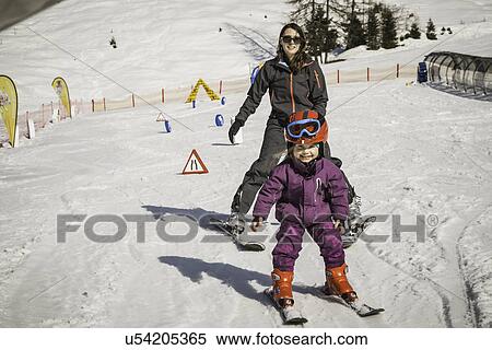 Stock Photography - "Mother and daughter skiing together, smiling". Fotosearch