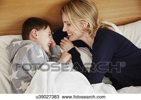 Stock Image - Mother and son laughing in bed. Fotosearch
