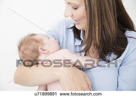Stock Image - Mother cradling baby in arms. Fotosearch